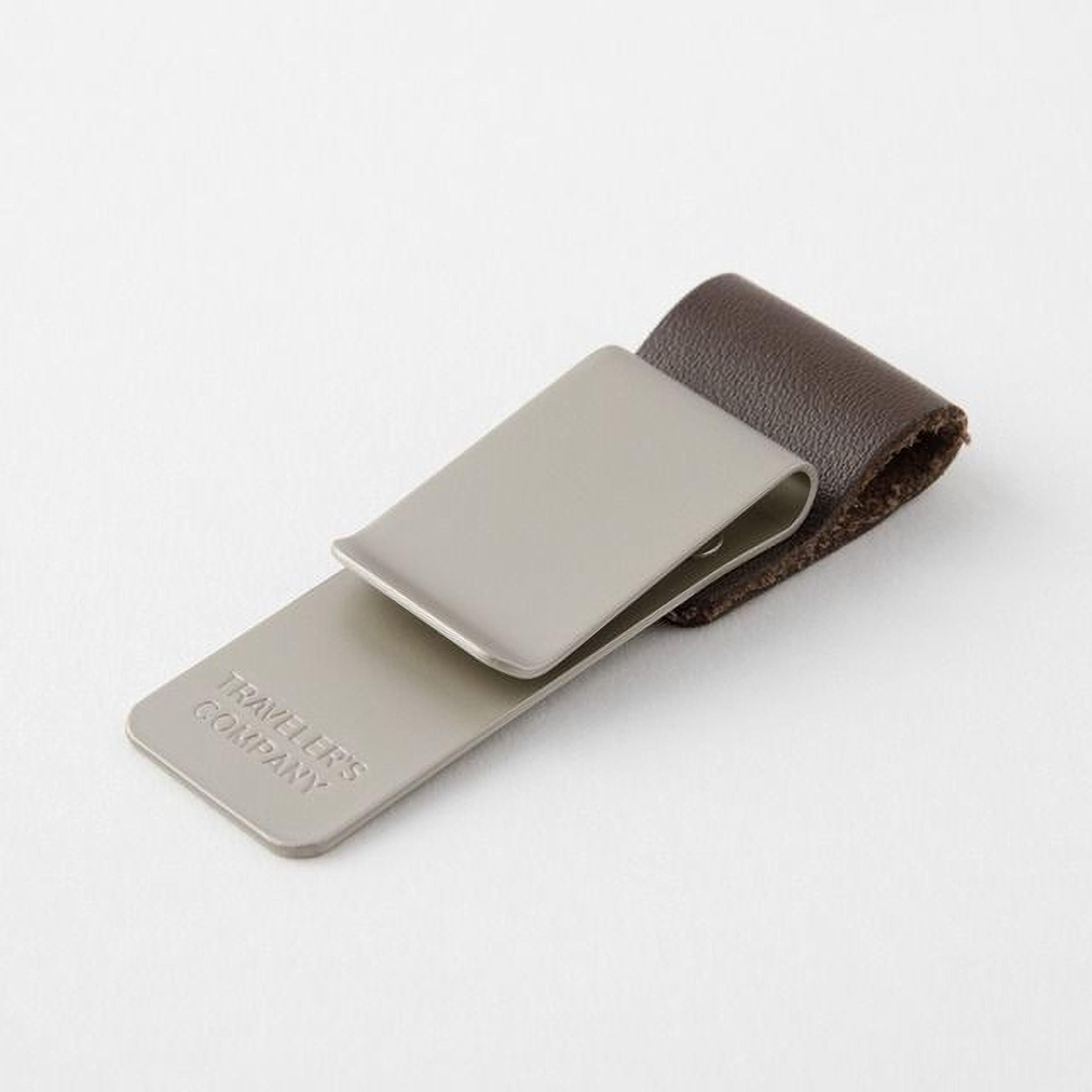 A grey metal money clip with a leather strap attached to it, resting on a white background.
