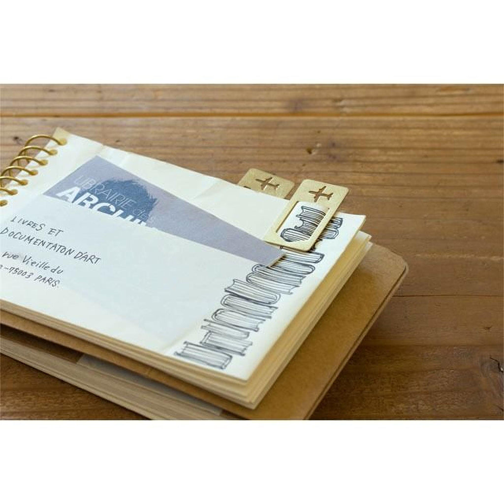 a spiral-bound notebook with a page displaying a drawing of books, placed on a wooden surface.