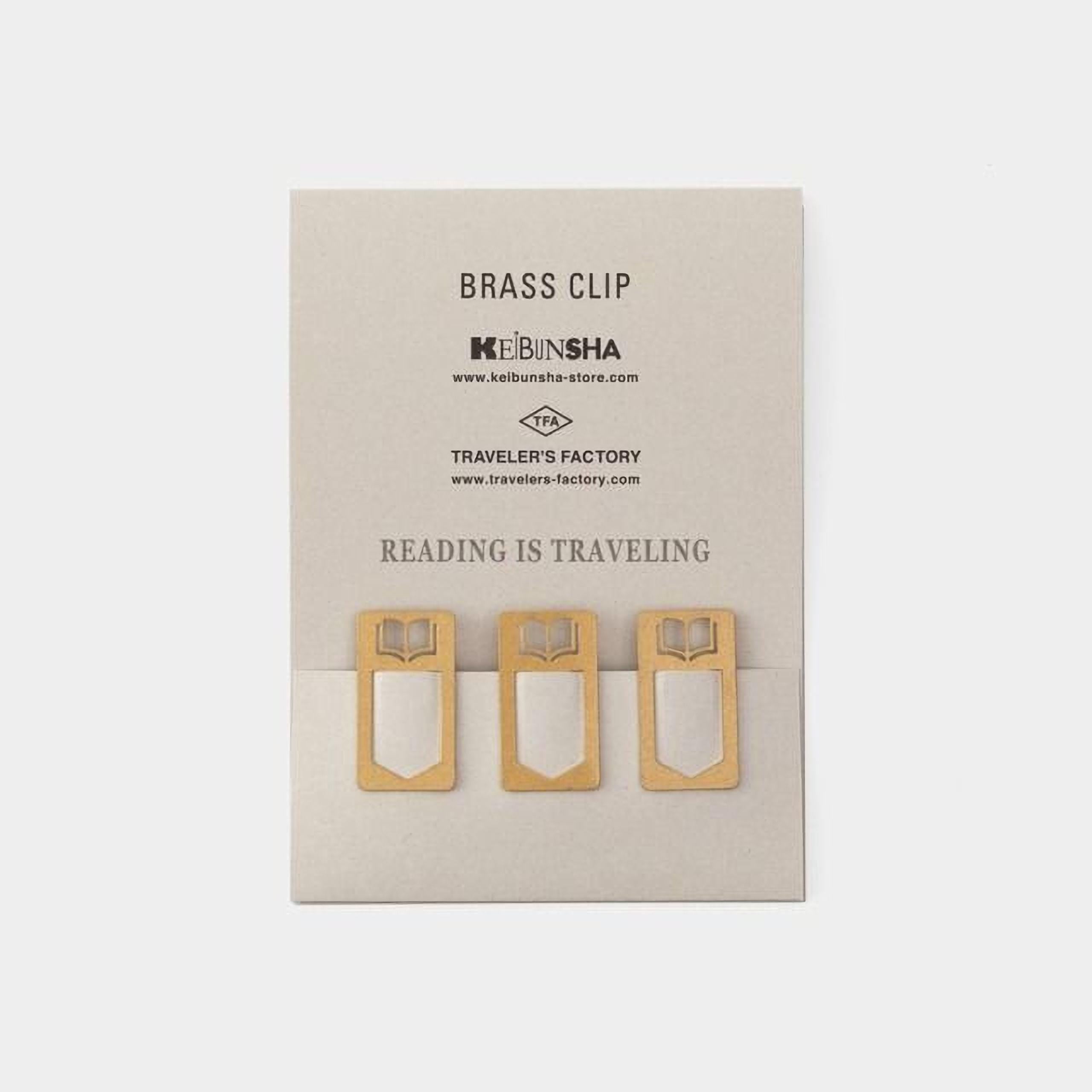 three brass clip holders with book-like designs, arranged on a light-colored background.