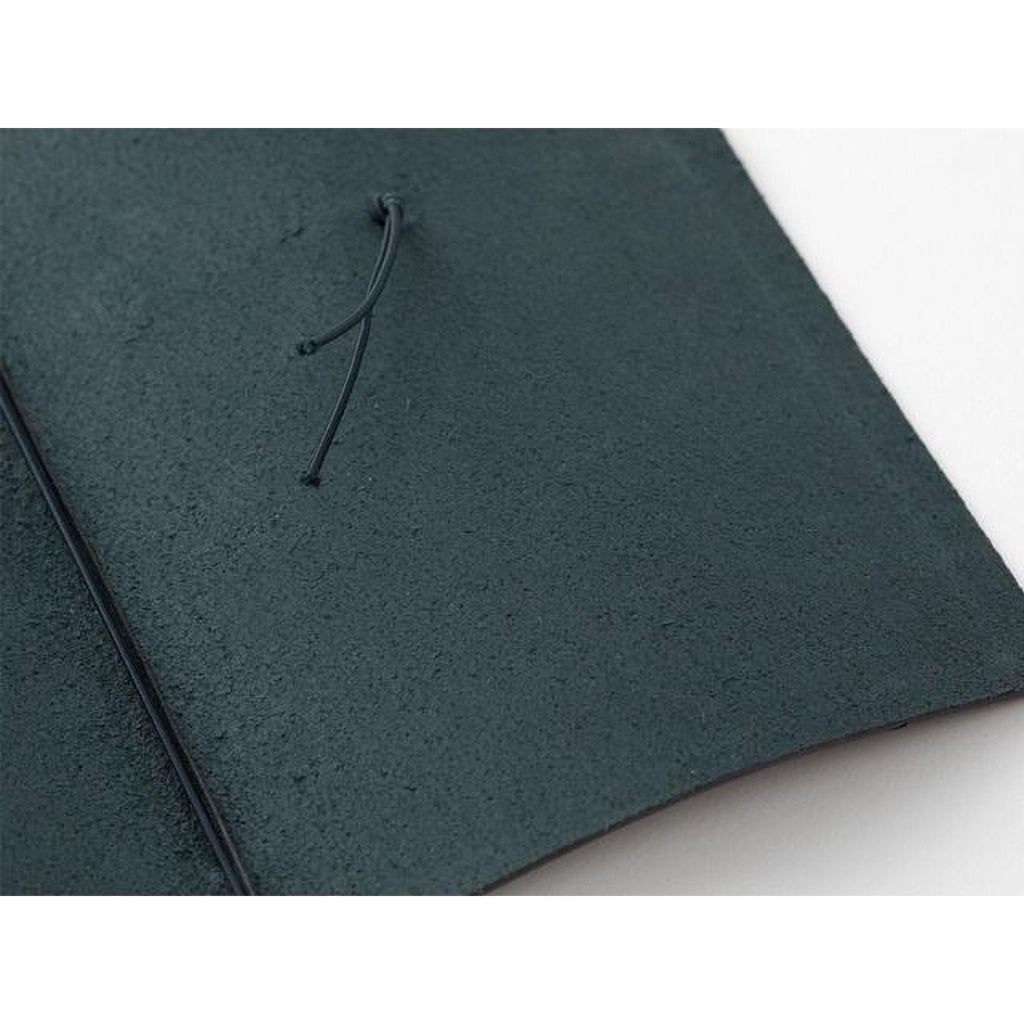 A close-up view of a dark green, textured surface with a black cord or string attached to it.
