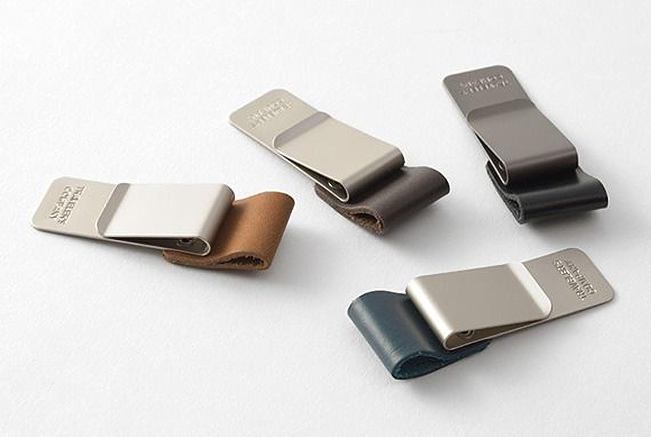 four different metal clip wallets, each with a unique design and color.