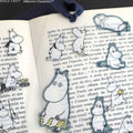 a collection of cartoon character stickers on a page of text, with various Moomin characters depicted in different poses and expressions.