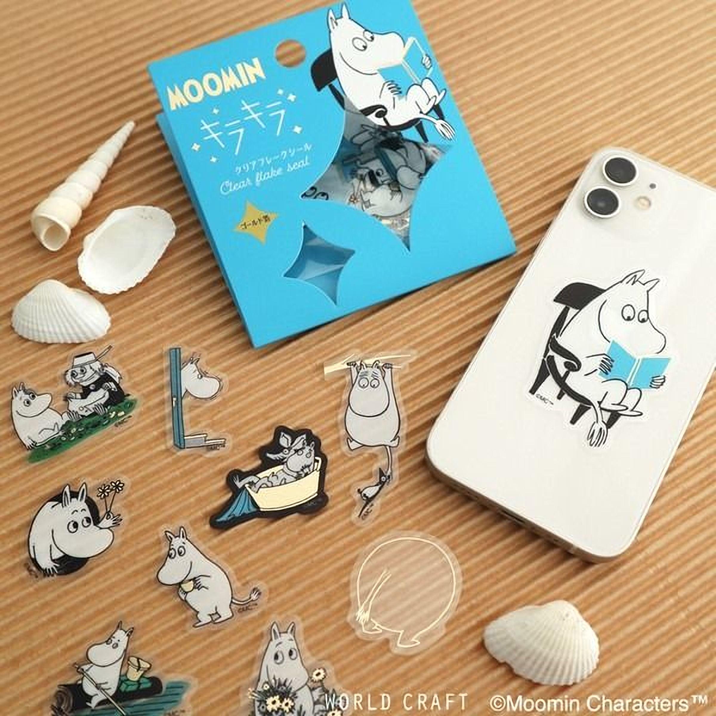 a collection of Moomin characters and accessories, including a blue box with a cartoon character, a smartphone, and various stickers and illustrations.