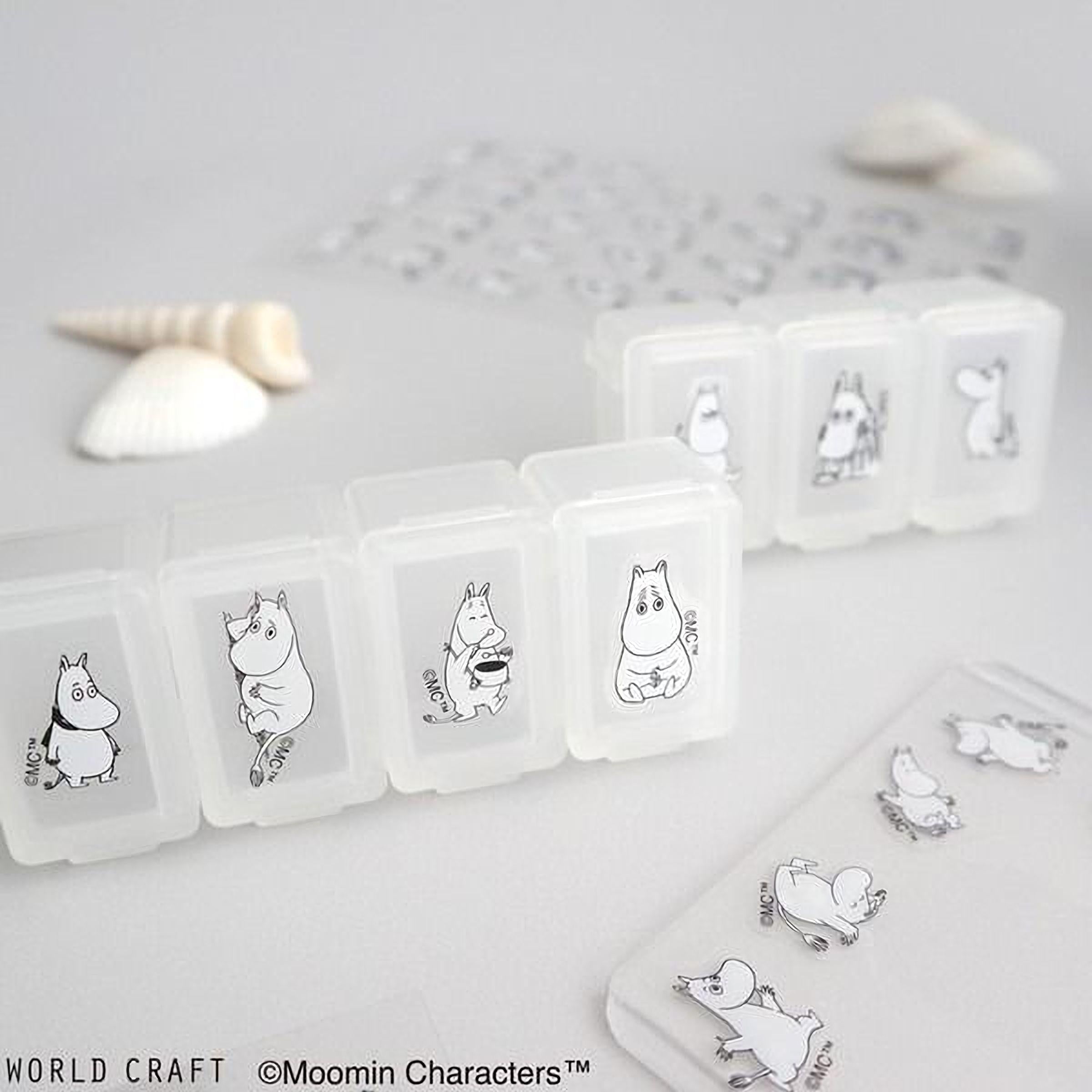 a collection of clear plastic containers with black and white illustrations of Moomin characters on them, along with some seashells and a small object.