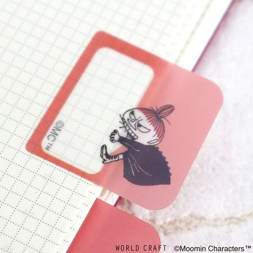 A pink bookmark with a cartoon character illustration on it, placed on a white grid background.