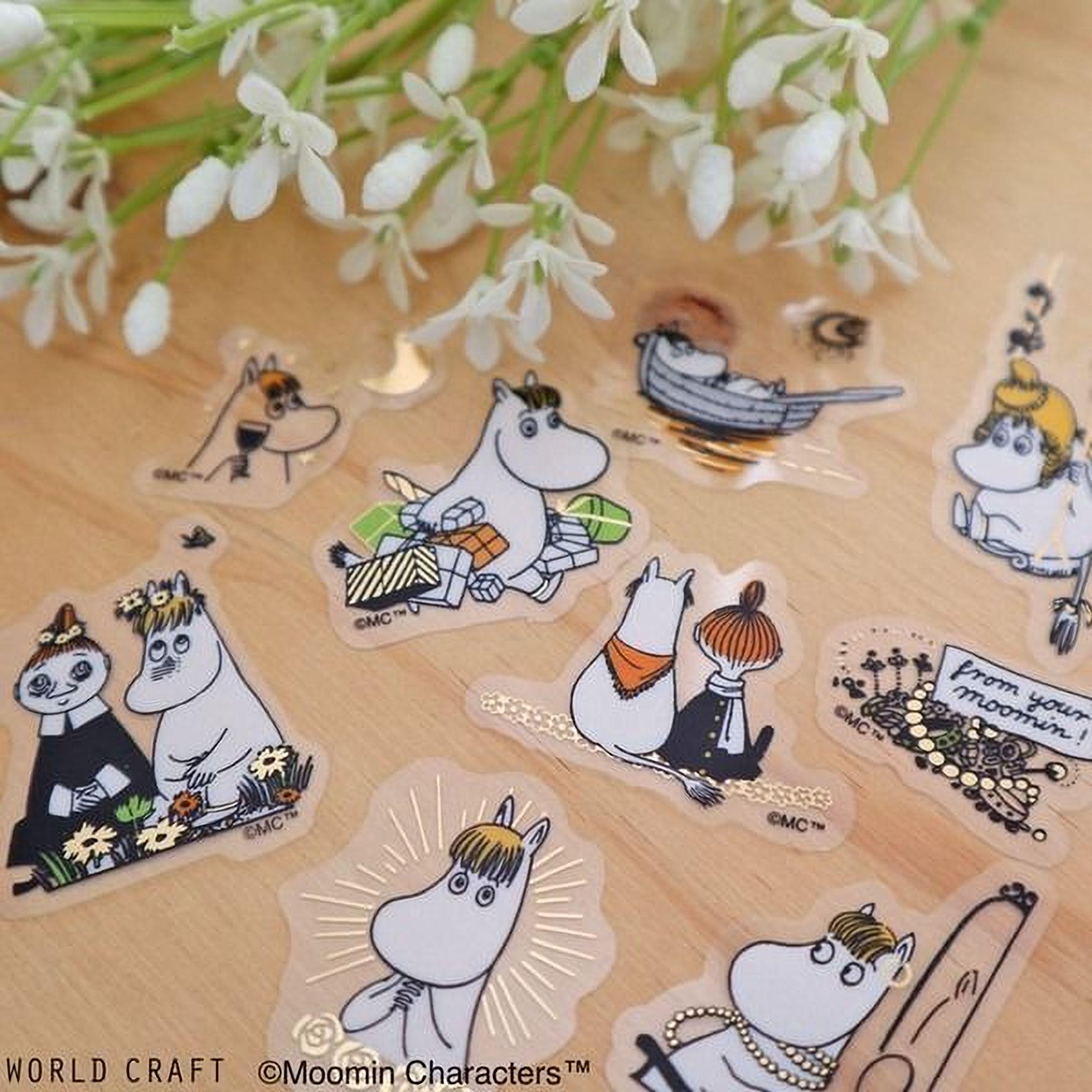 a collection of stickers featuring various cartoon characters, including Moomin characters, arranged on a wooden surface.