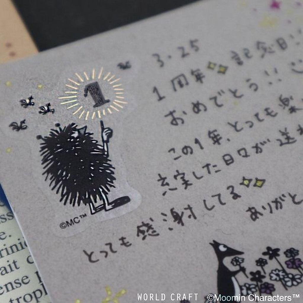 a close-up view of a piece of paper with Japanese text and a small illustration of a fuzzy black creature, possibly a hedgehog or a similar animal.