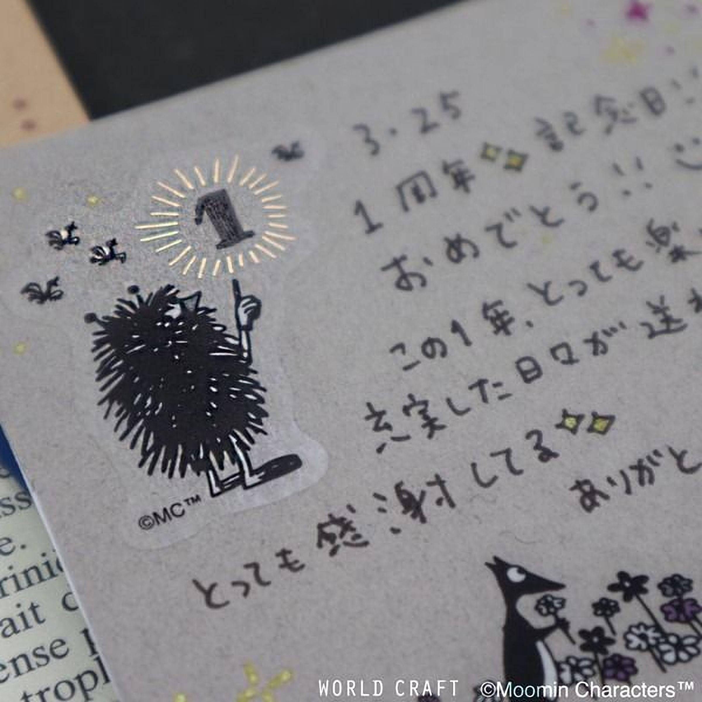 a close-up view of a piece of paper with Japanese text and a small illustration of a fuzzy black creature, possibly a hedgehog or a similar animal.