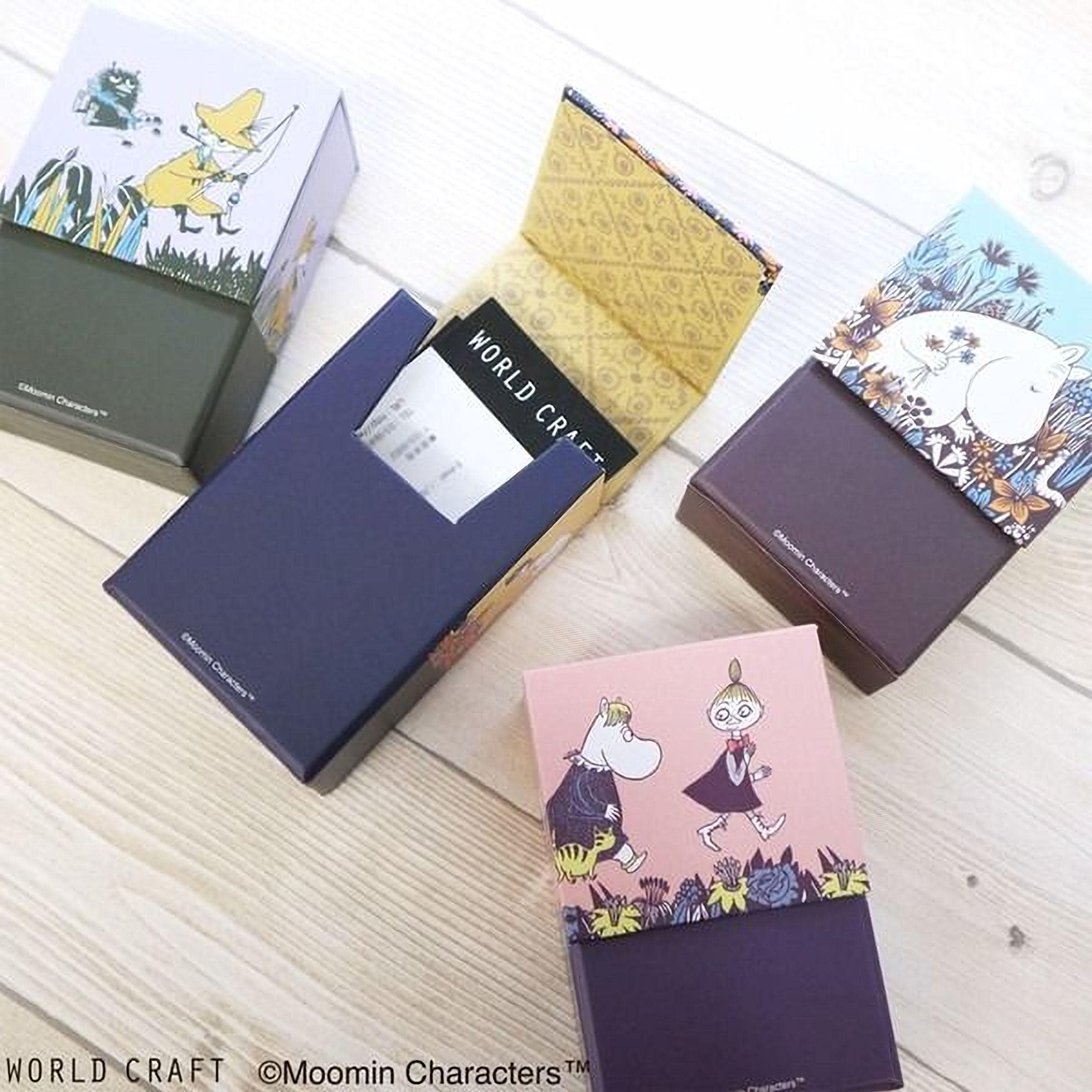 four colorful boxes with illustrations of Moomin characters, including a character with a yellow hat and a character with a pink dress.