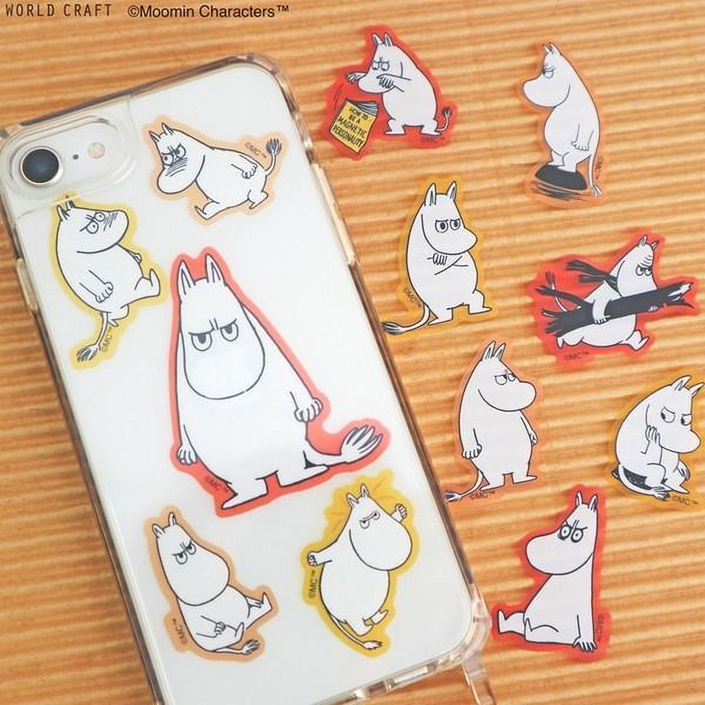a collection of stickers depicting various Moomin characters, including the main character Moomin, arranged on a wooden surface.