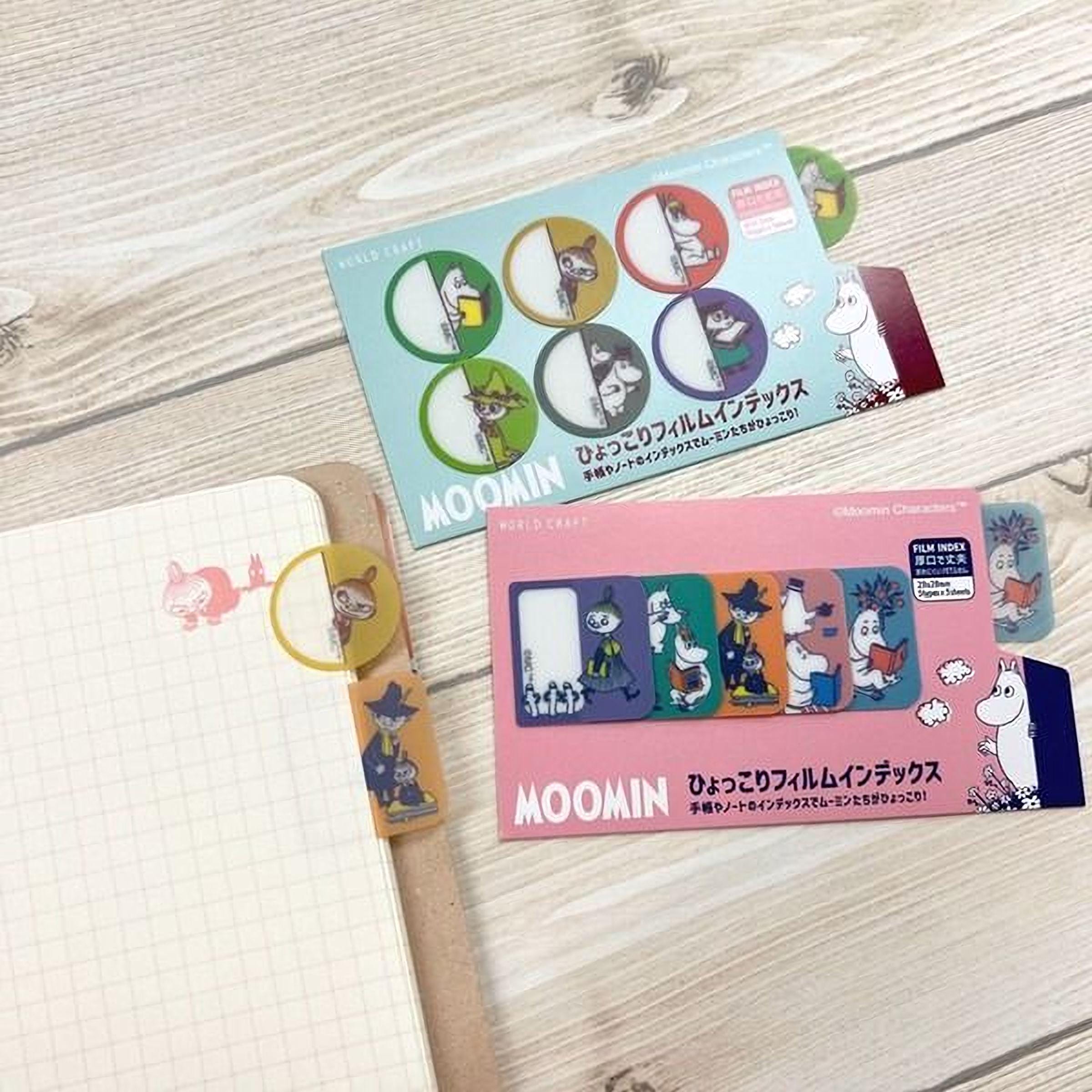 a collection of colorful Moomin character stickers and a notebook with a grid pattern.