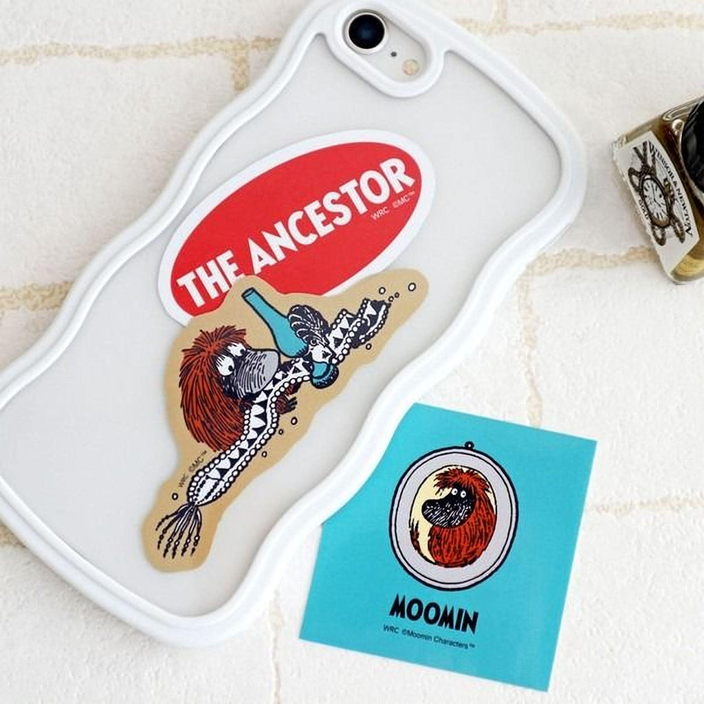 a white phone case with a sticker and a blue sticker on it, along with a small object and a blue sticker with a character on it.