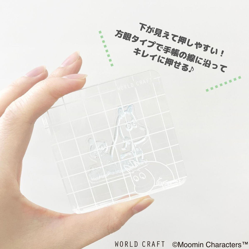 A hand holding a clear plastic object with a grid pattern on it, against a white background with Japanese text.