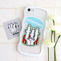 a phone case with a sticker of a group of cartoon-like figures, along with a card featuring a similar design. The phone case and card are placed on a white surface, with white flowers visible in the background.