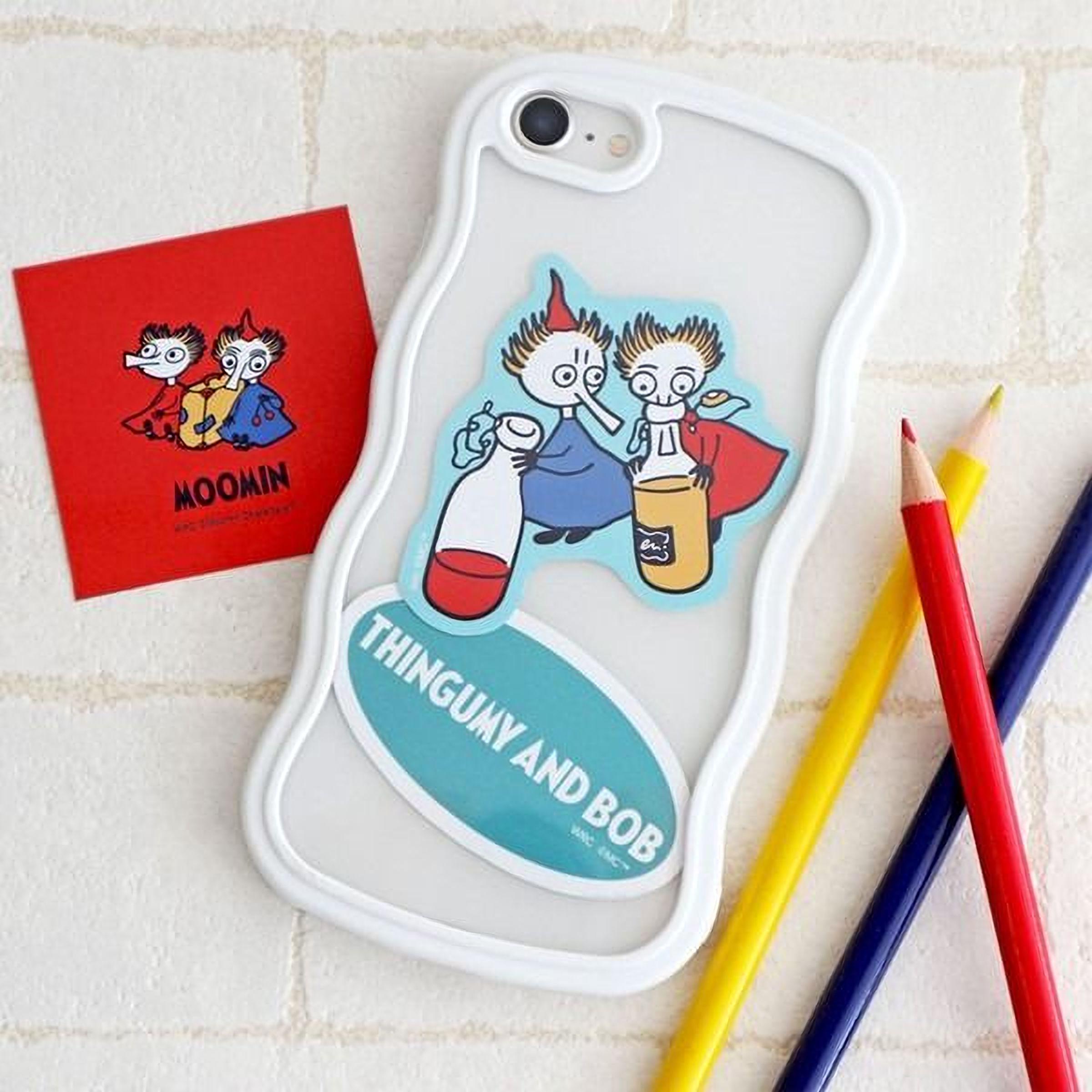 a phone case with a sticker of two cartoon characters, along with a red sticker and some colored pencils.