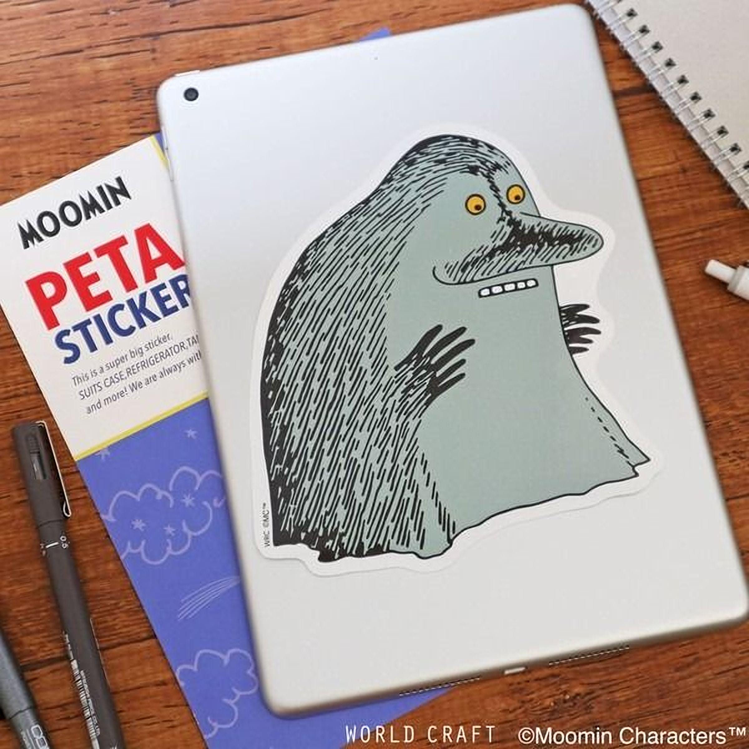 a sticker of a cartoon character on a tablet, along with some stationery items such as a notebook and pens.