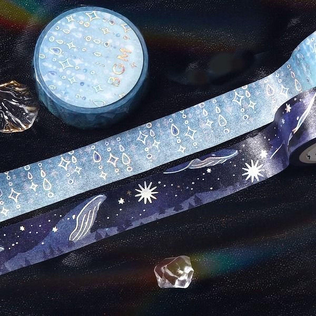 a collection of various items, including a blue and white star-patterned tape, a small blue and white star-patterned box, and a clear crystal.