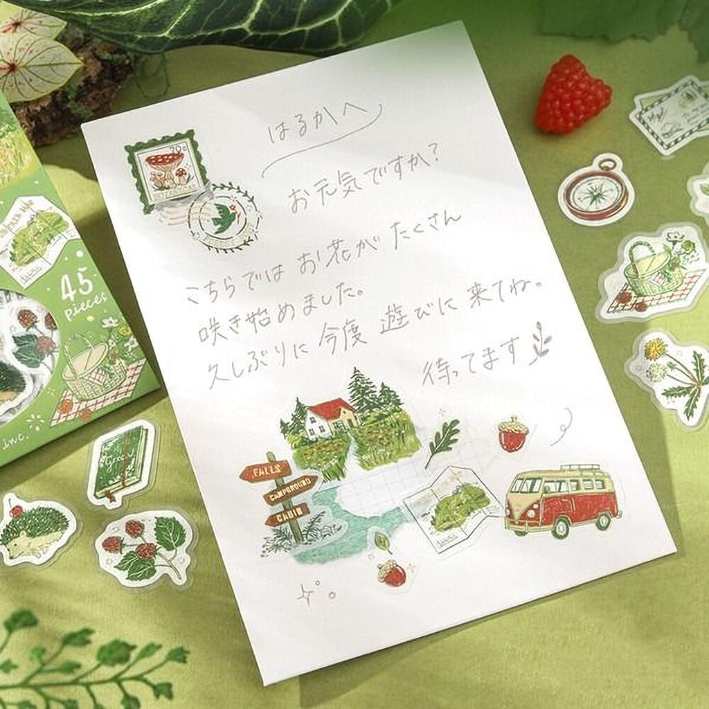 a handwritten note on a piece of paper, surrounded by various stickers and illustrations, including a red raspberry, a compass, and a van.