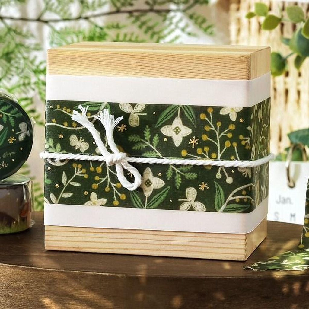 A wooden box with a green and white floral patterned wrapping tied with a white string, placed on a wooden surface.