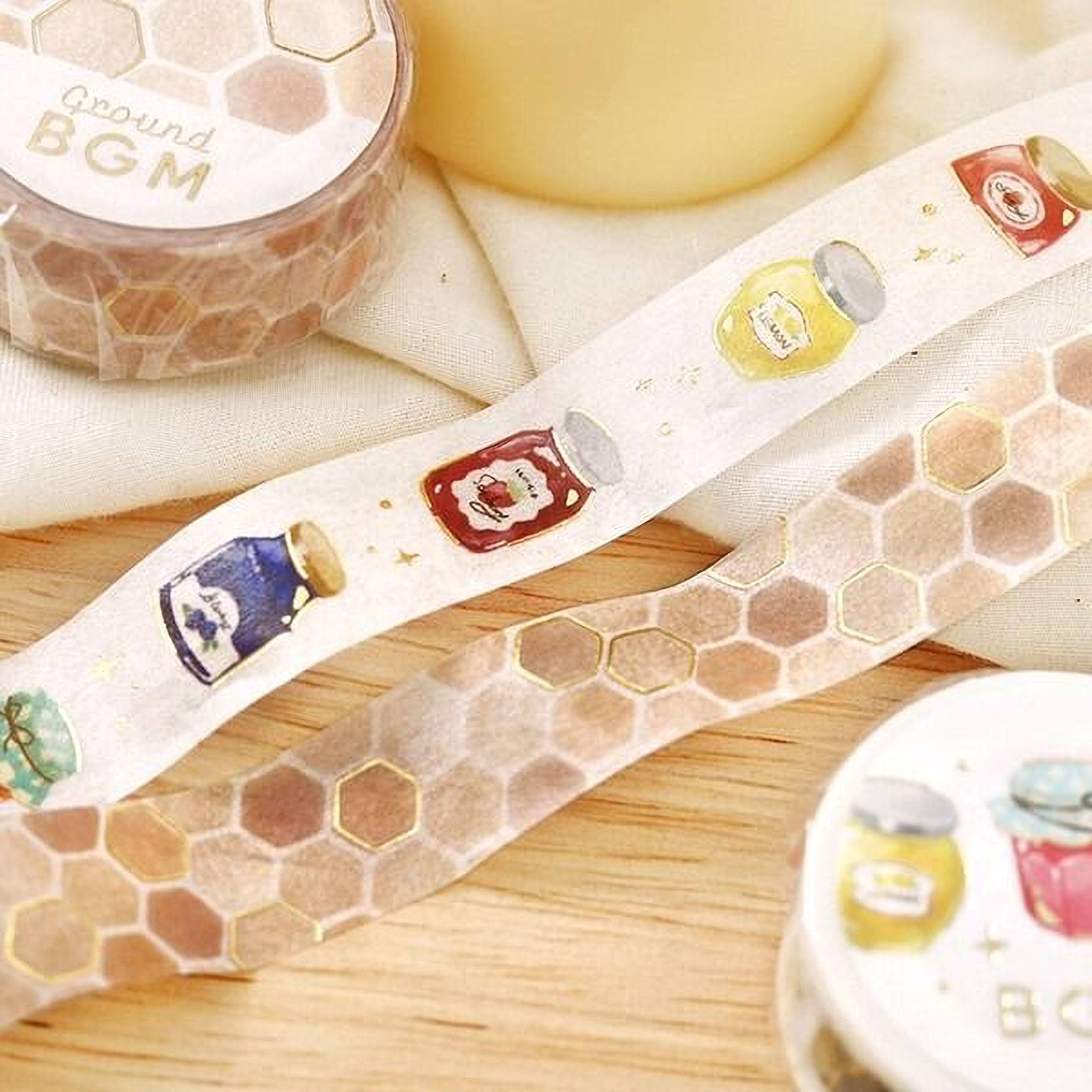 a collection of decorative items, including a honeycomb-patterned tape dispenser, a jar of honey, and a round container with a honeycomb pattern.