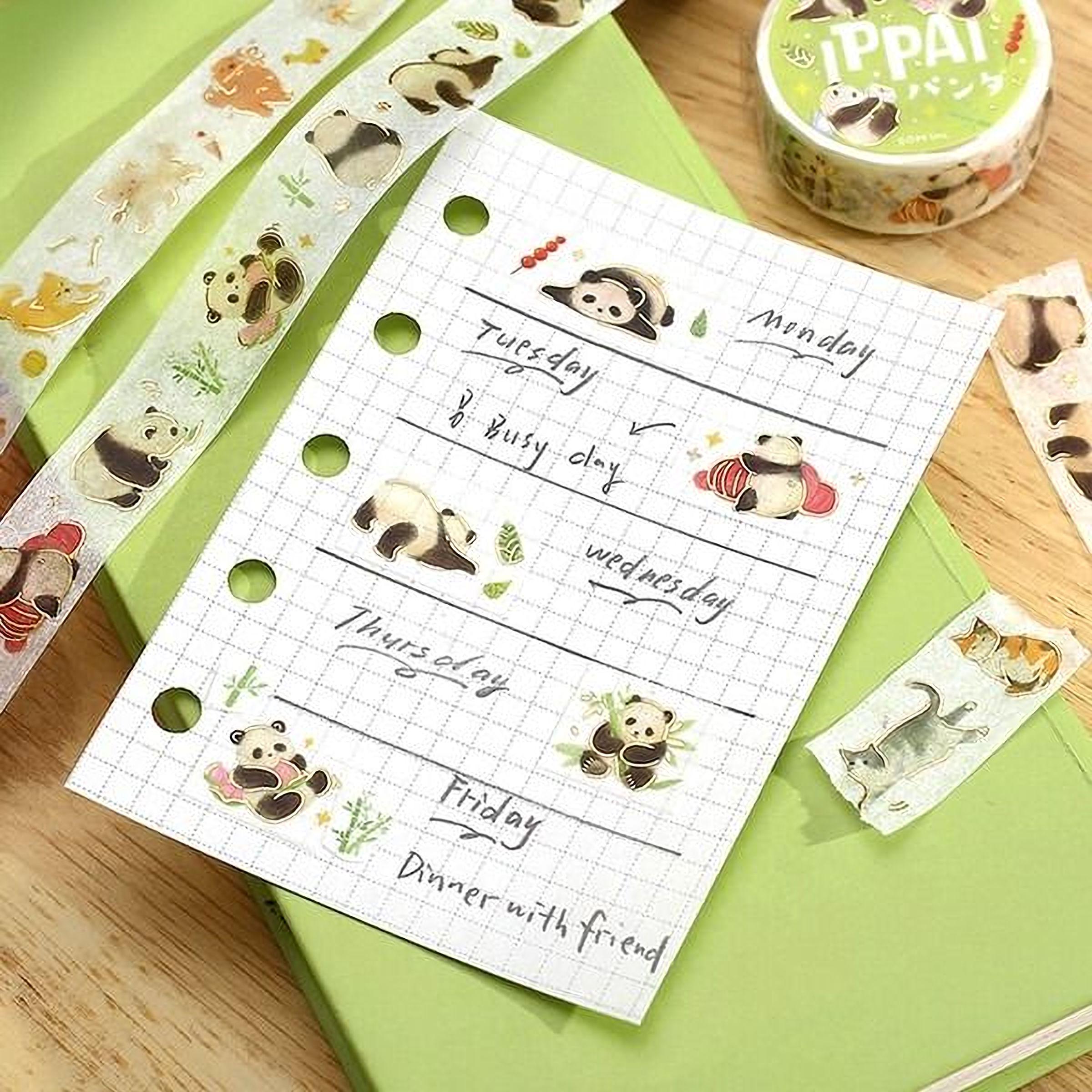 a notebook with a grid layout, containing illustrations of pandas and a calendar for the week. There is also a green notebook and a tube of LESS THAN 500 characters tape with a panda design.