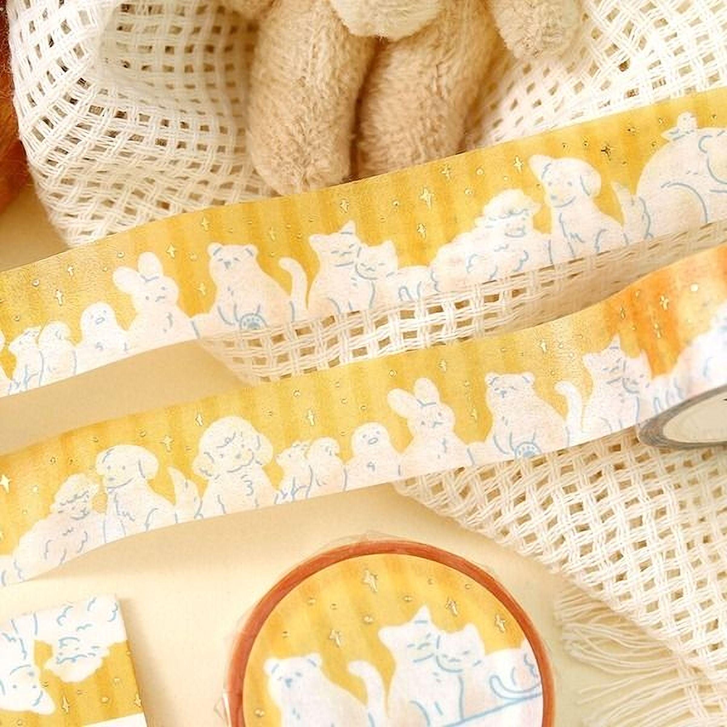 a yellow and white striped tape with a playful cat and dog design, along with a small round container with a similar cat and dog design.