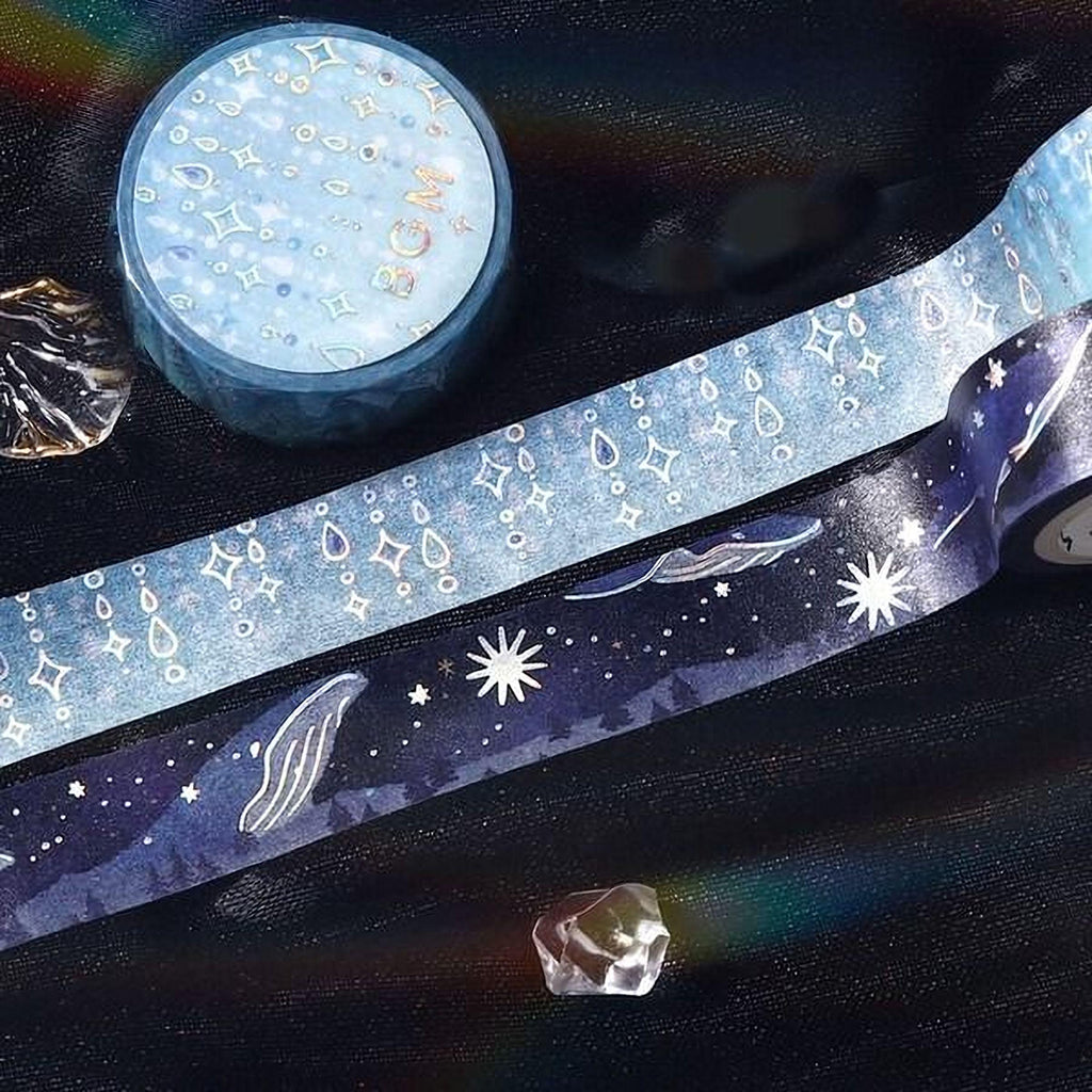 a collection of various items, including a blue and white star-patterned tape, a small blue and white star-patterned box, and a clear crystal.