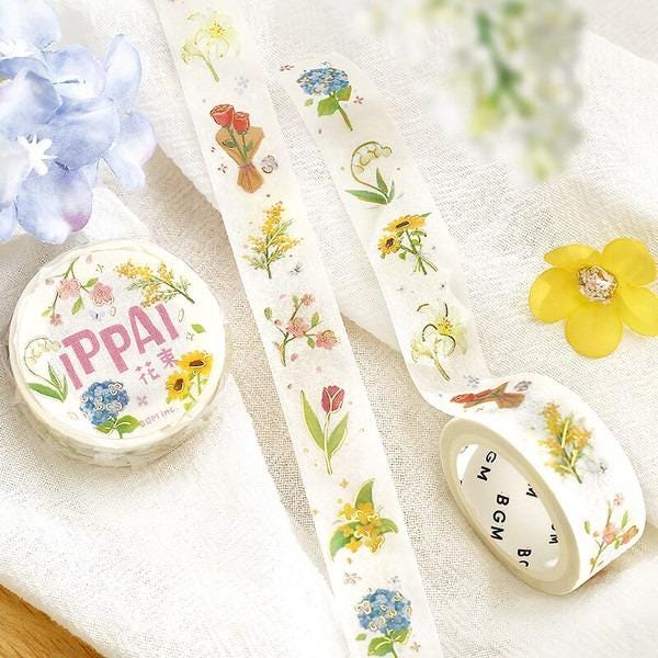 a variety of decorative items, including a round container with a floral design, two rolls of floral patterned tape, and a yellow flower.