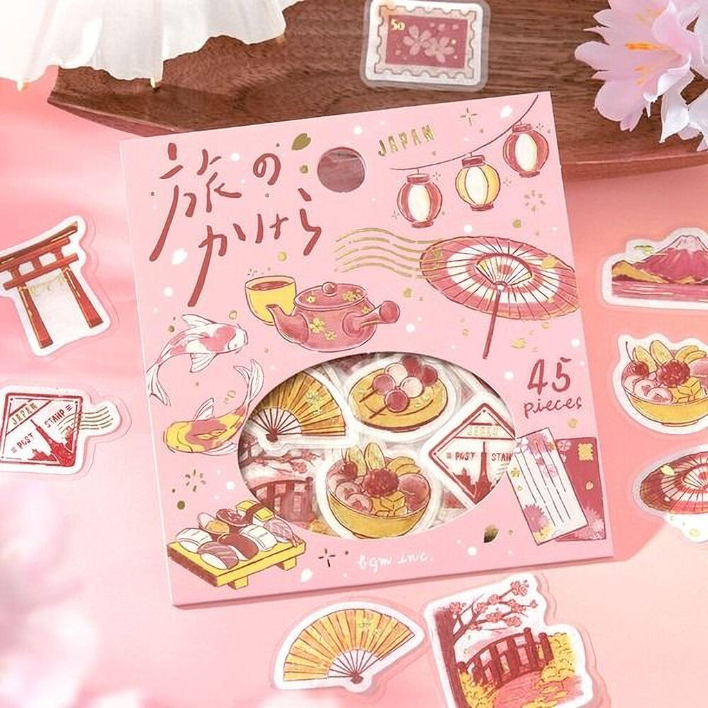 a pink box with various Japanese-themed stickers and illustrations, including a torii gate, lanterns, and other cultural elements.