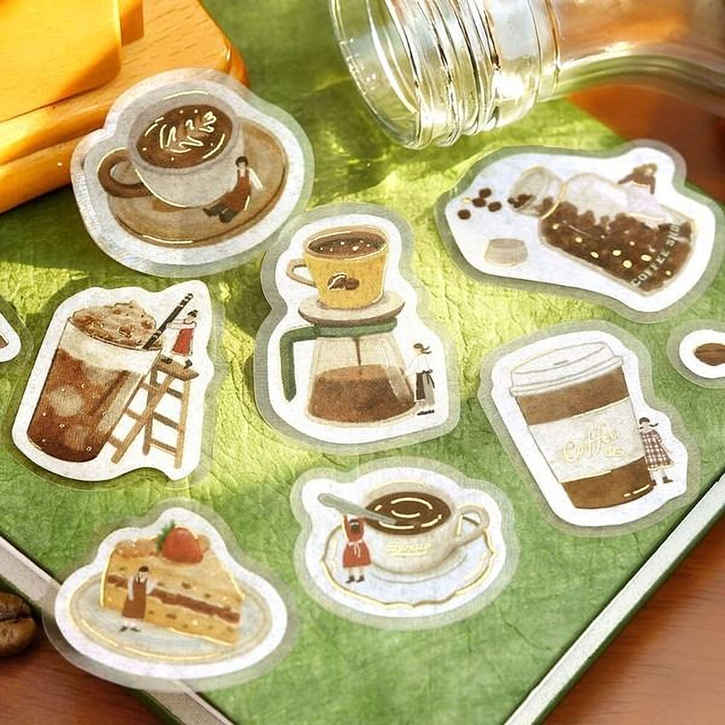 a collection of stickers depicting various coffee-related items, such as cups, mugs, and coffee-making equipment, arranged on a green surface.