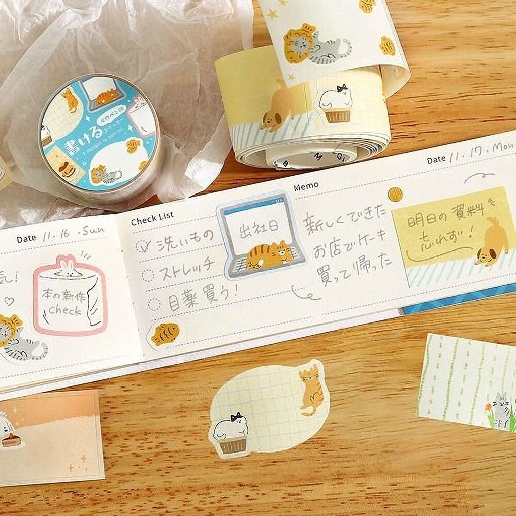 a collection of various items, including a roll of tape, a notebook, and some stickers, all placed on a wooden surface.