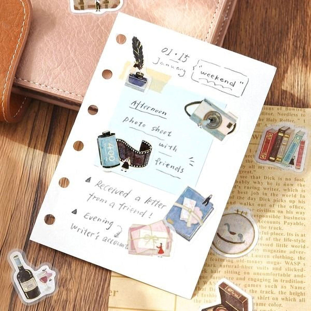 The image is a notebook page with various stickers and illustrations, including a camera, books, and a letter opener. The page also contains handwritten notes and a list of items, such as "Afternoon photo sheet with friends" and "Received a letter from a friend!"