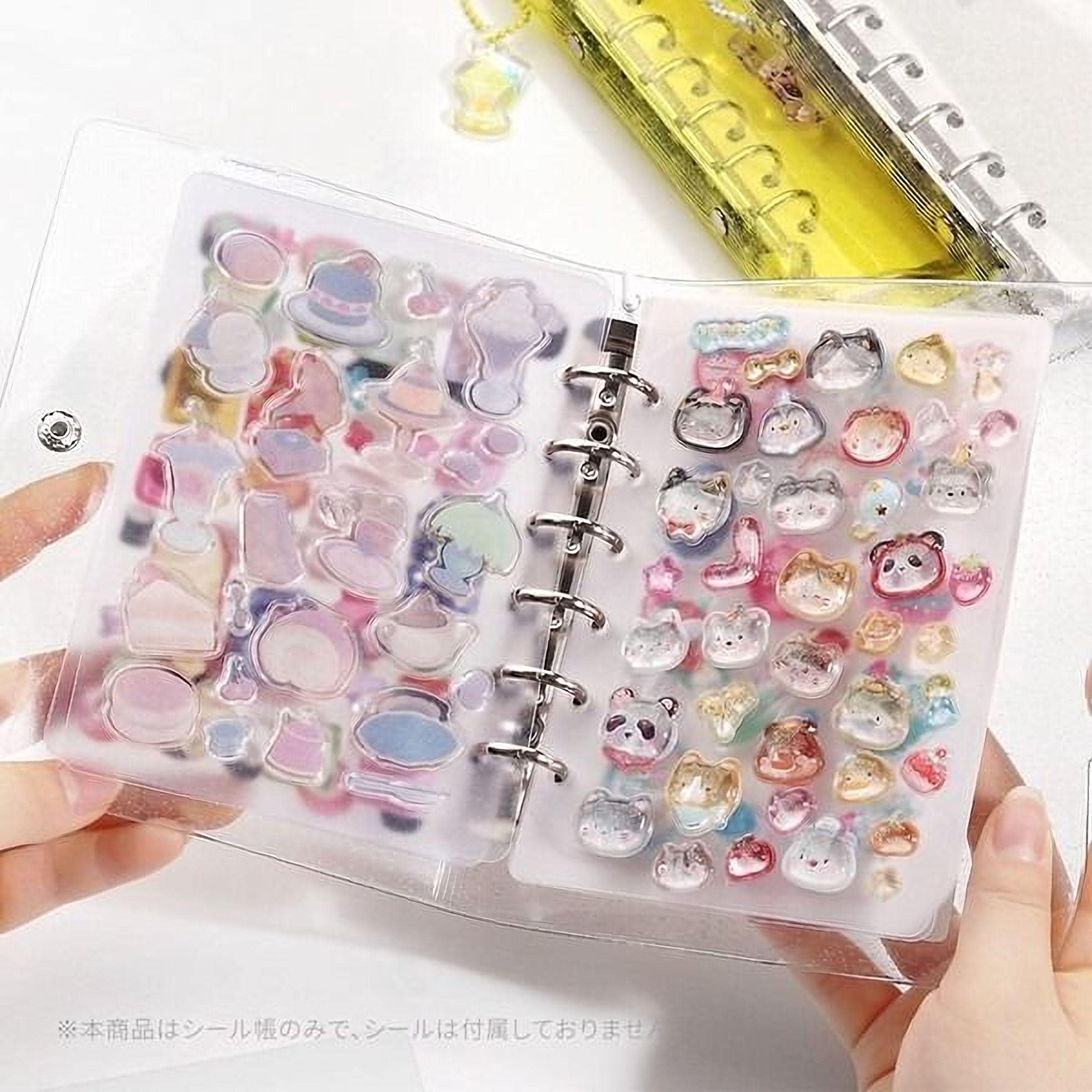 A person's hands holding an open binder with a clear plastic cover, revealing a collection of colorful stickers and magnets.