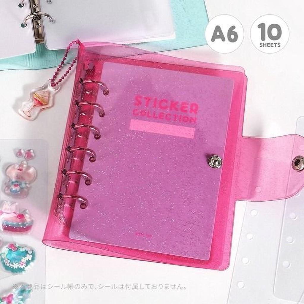 A pink glittery notebook with a spiral binding and a keychain attached, along with some other small items, such as a keychain and a keychain.
