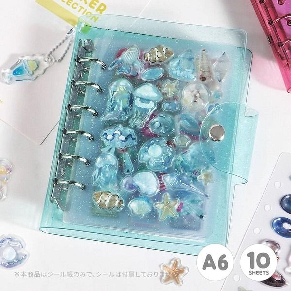 A transparent, glittery, and colorful organizer with various sea-themed items, such as jellyfish, starfish, and seashells, displayed inside it.