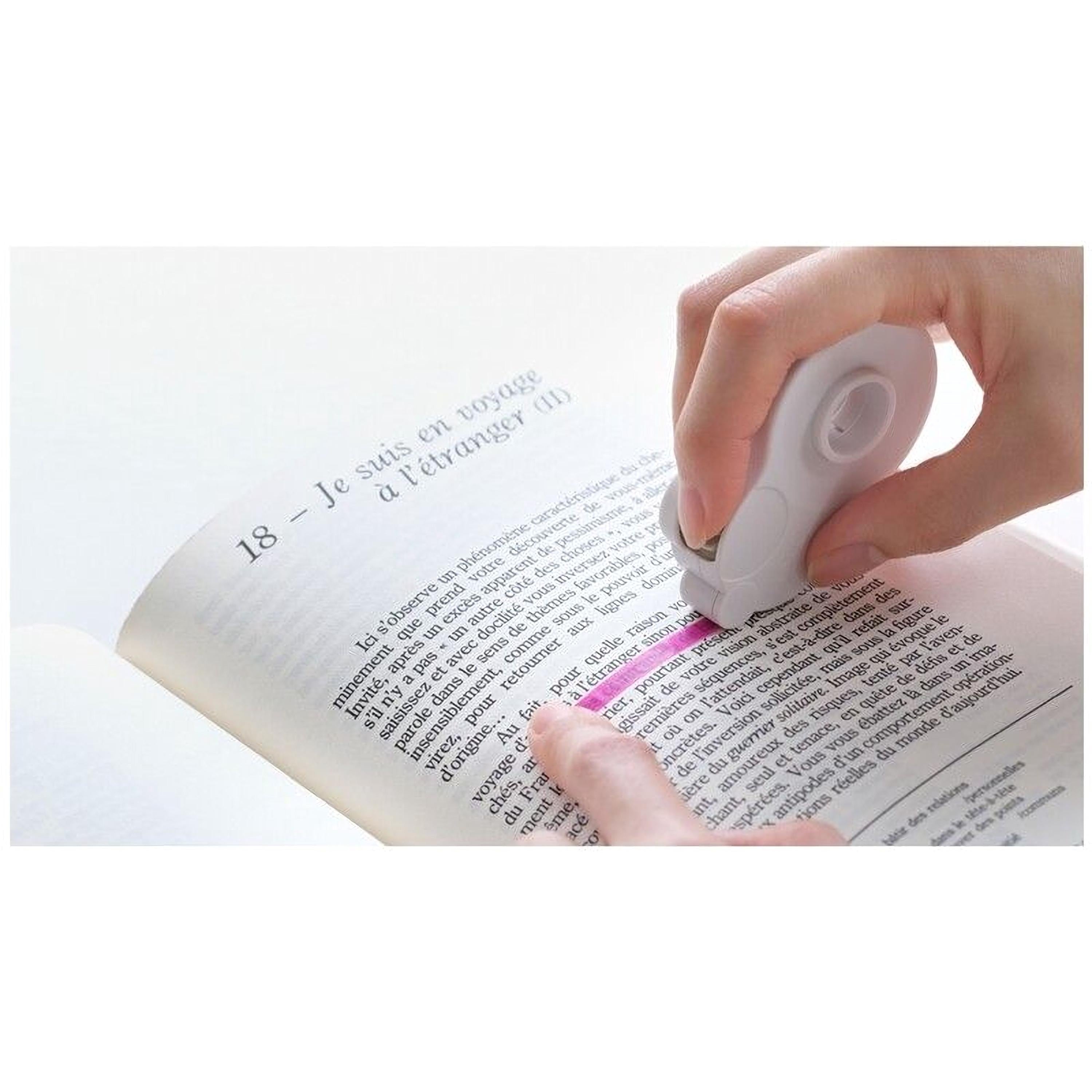 A person's hand is using a white stapler to staple a page from a book.