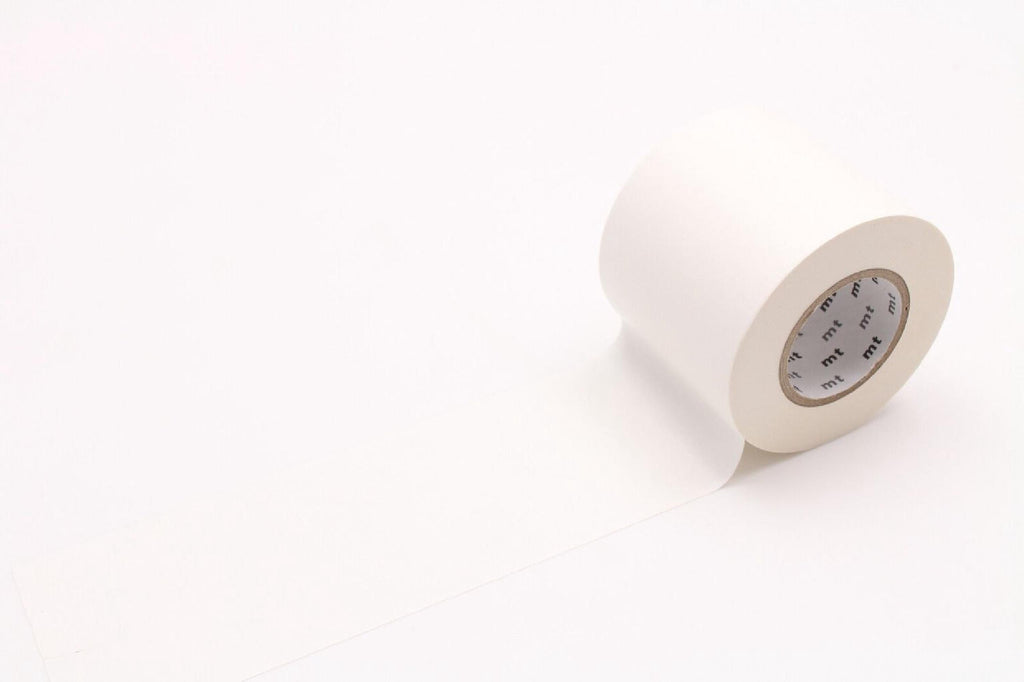 A roll of white tape is lying on a white surface.