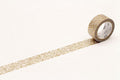 A roll of gold glittery tape is lying on a white surface, with a single gold glittery line drawn on the surface.