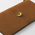 A brown leather-like notebook with a gold-colored button on the cover.