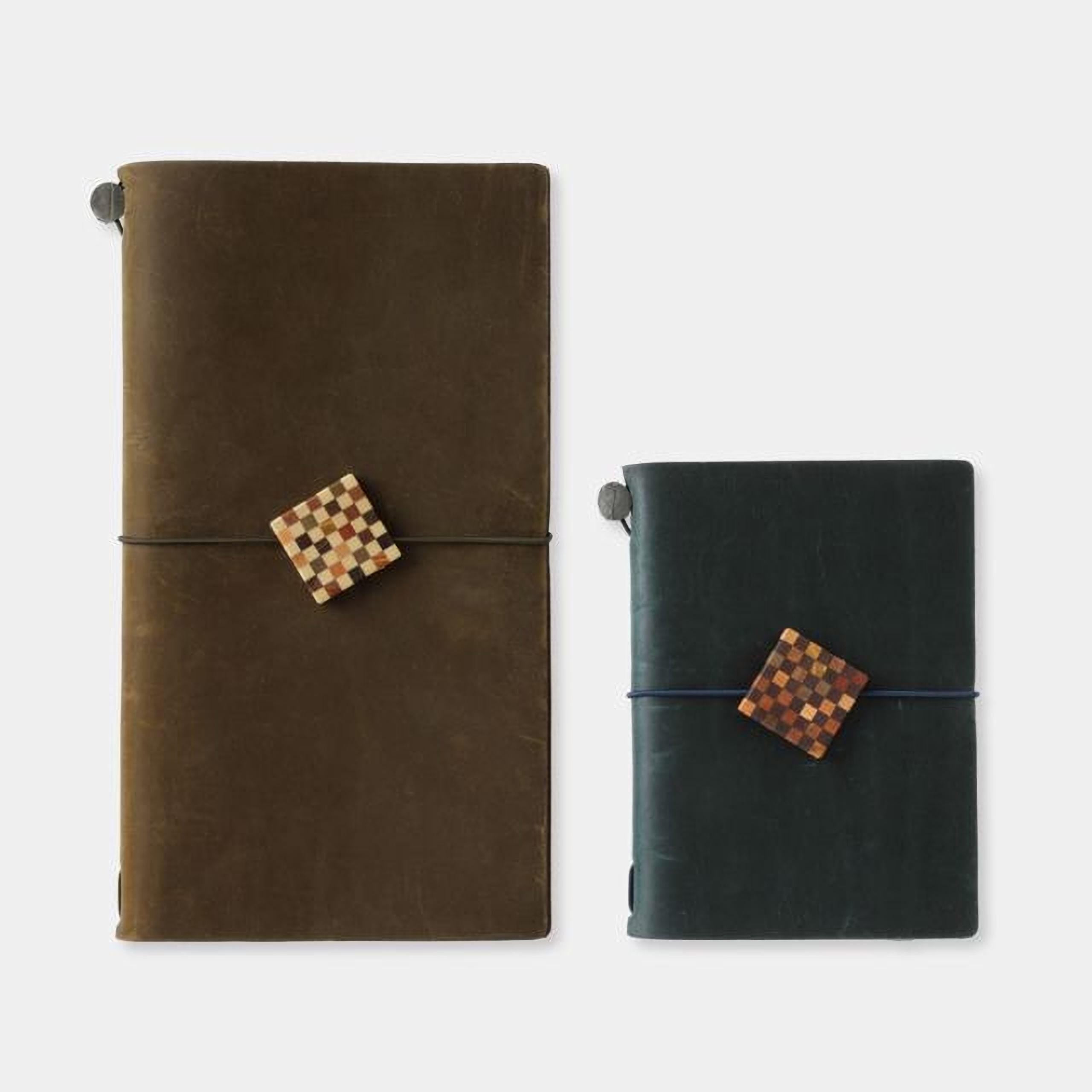 Two leather-bound notebooks with checkered designs on the covers, one in a dark brown color and the other in a dark green color.