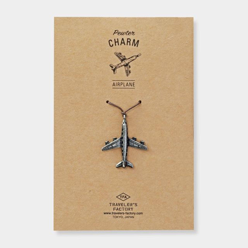 a small airplane charm on a brown background.