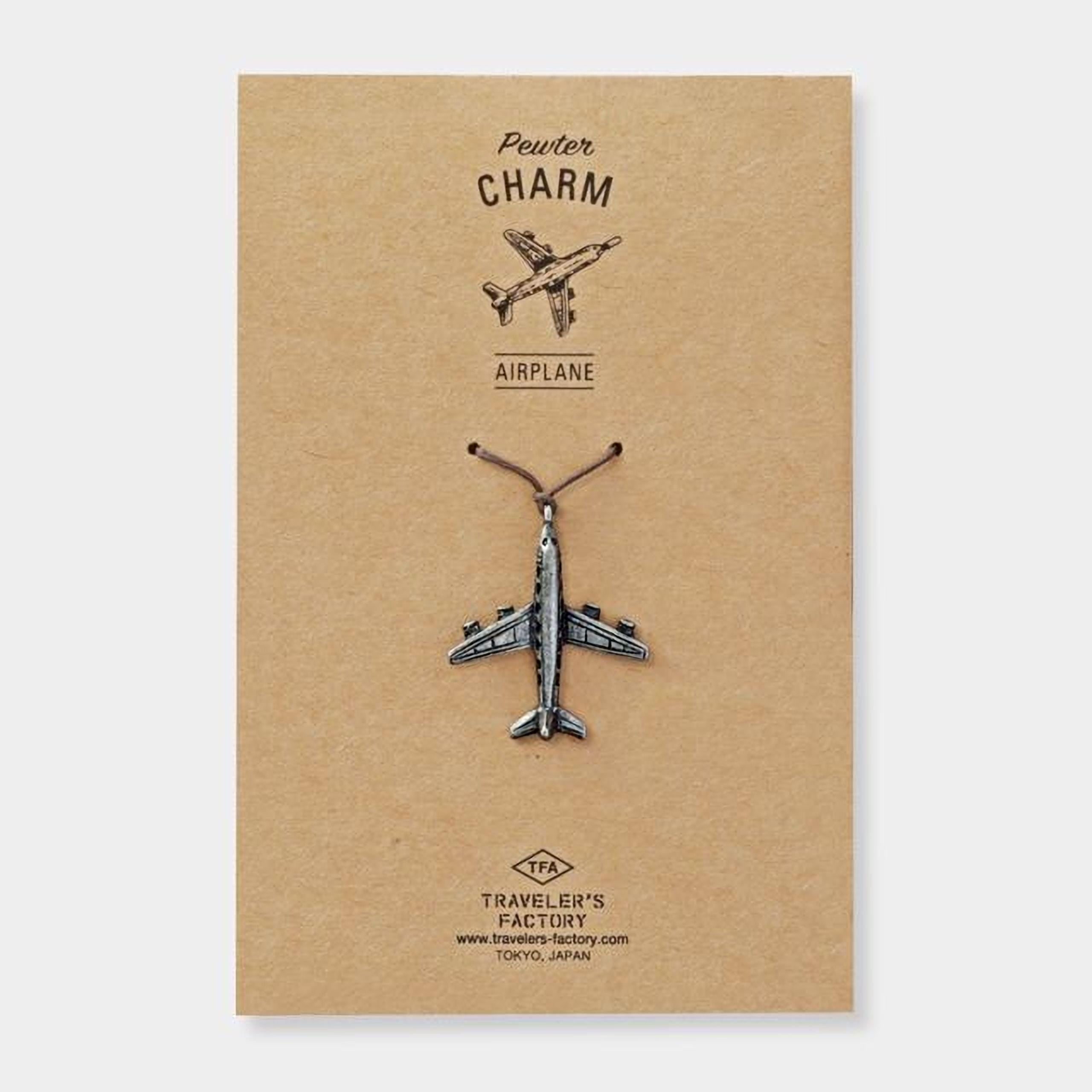 a small airplane charm on a brown background.