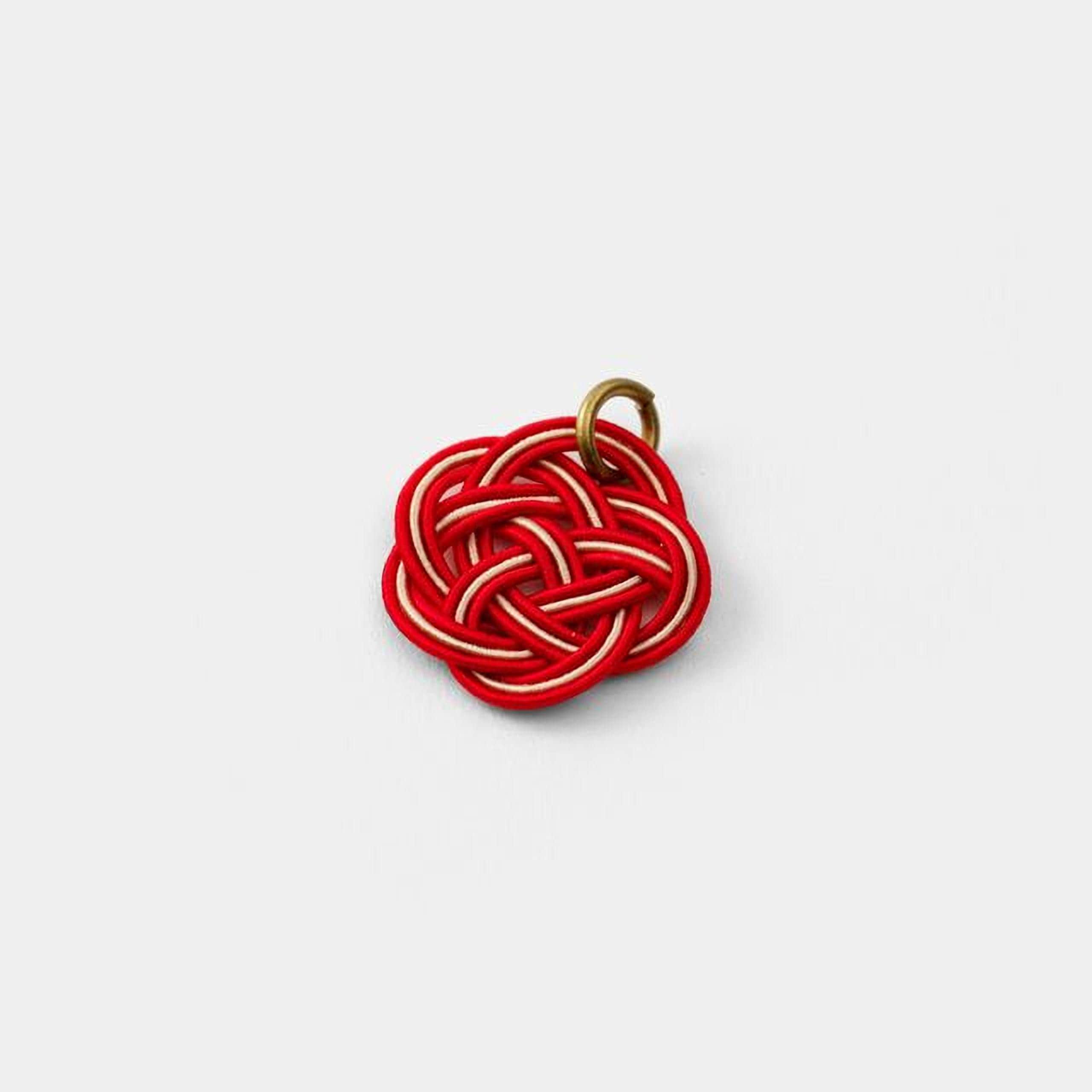 A red and white knot-like object with a gold clasp attached to it.