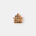 A small, colorful house-shaped object made of small squares or rectangles in various shades of brown, orange, and beige.
