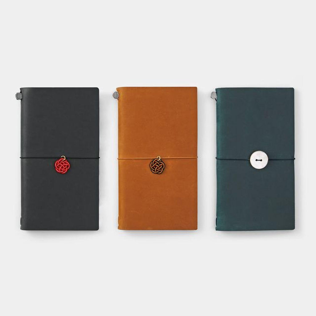 Three different colored notebooks or planners are arranged in a row, each with a unique design and color.