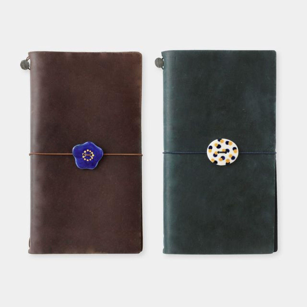 two leather-bound notebooks with decorative buttons on the covers.