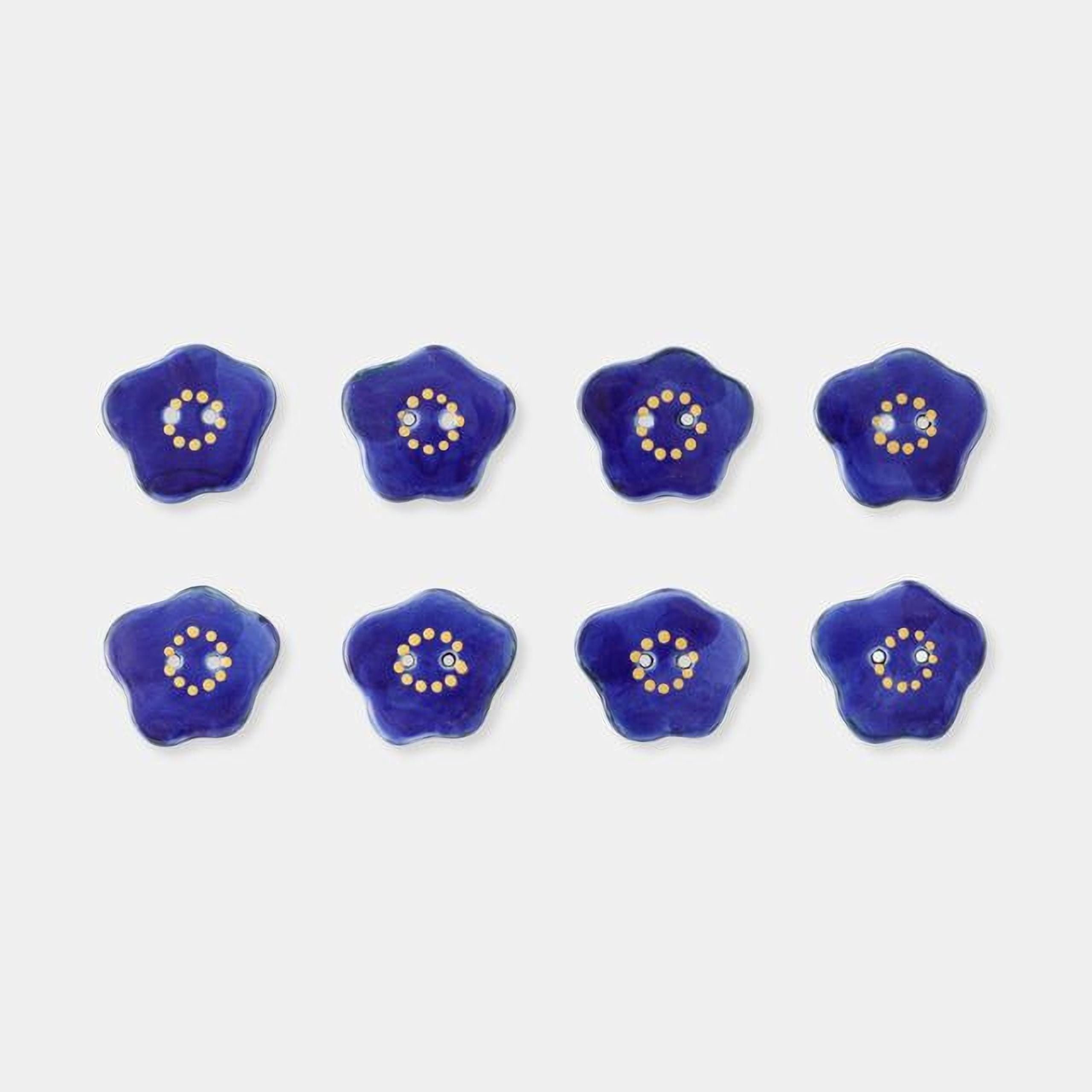 eight blue flower-shaped objects with yellow centers, arranged in a grid-like pattern against a white background.