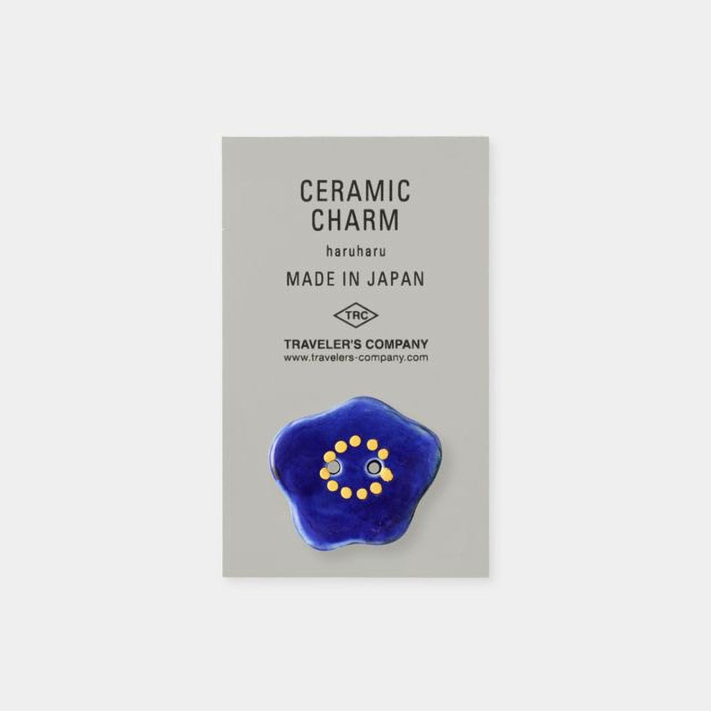 The image is a product advertisement for ceramic charms, specifically the "Ceramic Charm Haruharu Made in Japan". The product is described as a "Ceramic Charm" and is made in Japan. The ad also mentions that the product is from the "Traveler's Company" and includes a website address for further information.