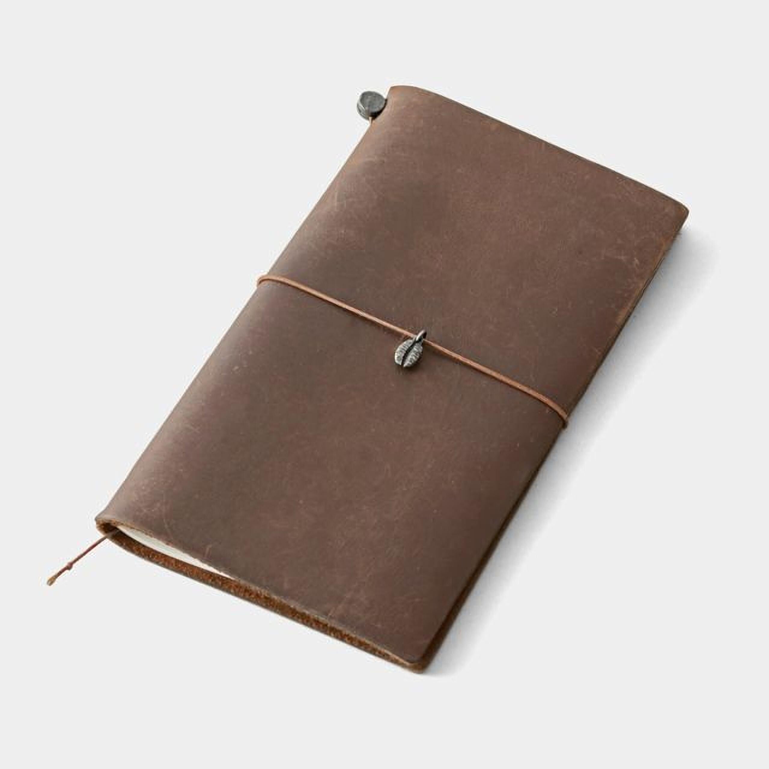 A brown leather-bound notebook with a metal clasp and a small metal charm on the cover.