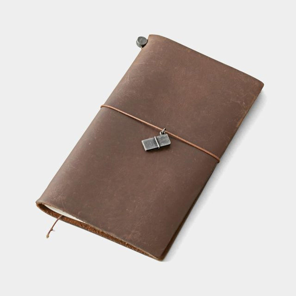 A brown leather-bound notebook with a metal clasp and a small metal charm attached to the cover.